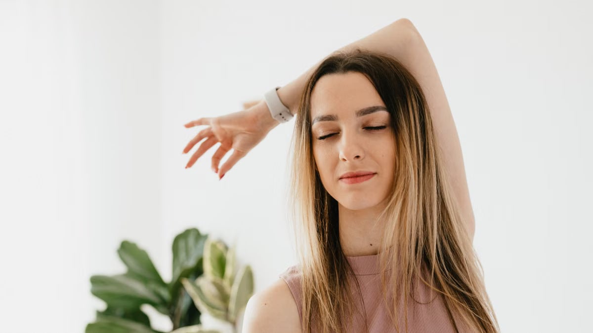 Peaceful young female doing Gyan mudra while meditating during yoga session at home